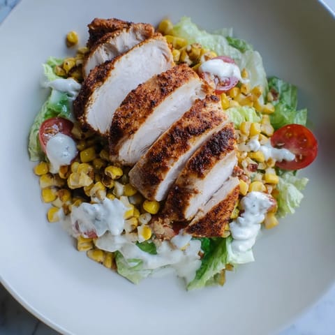 A hearty BBQ Chicken Salad features juicy grilled chicken over fresh greens, with vibrant corn, black beans, and a cool ranch finish.  