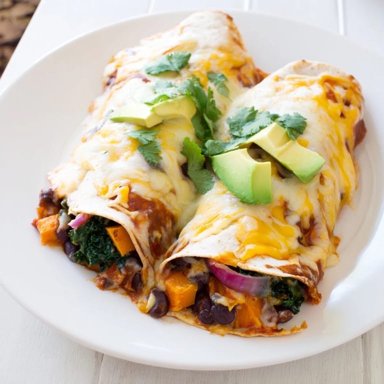This one-pan sweet potato, black bean & kale enchiladas dish features brightly colored vegetables and melted cheese aromas.
