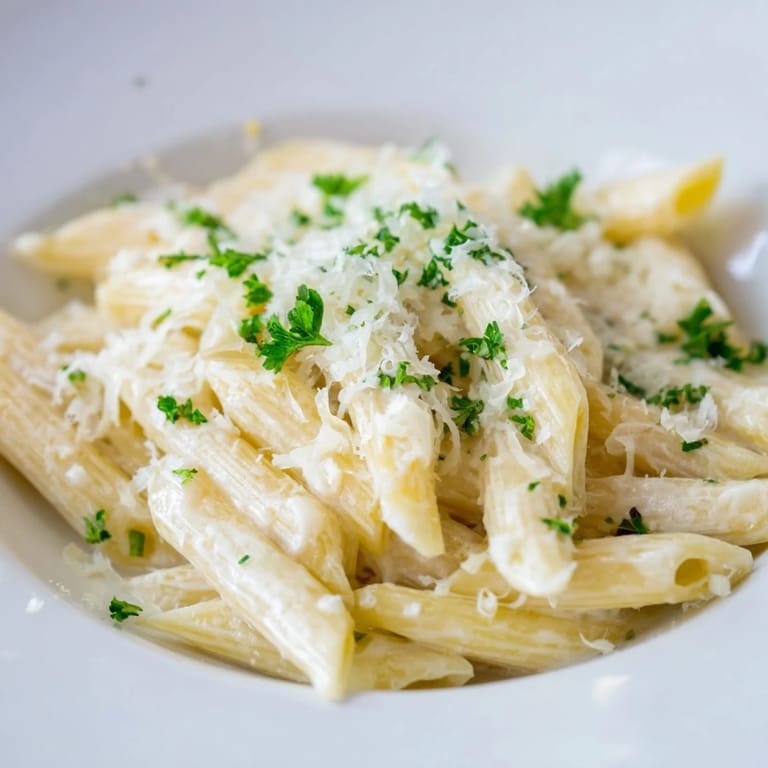A close-up of a bowl filled with comforting Creamy Milk Pasta garnished with fresh parsley. 